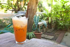 Iced milk tea in modern glass with natural garden view, Thai drink photo