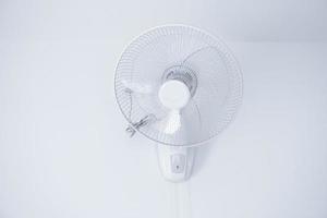 Wall mount electric white fan,electric fan hanging on white mortar wall photo