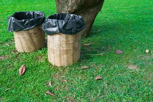 Trash bin made of bamboo baskets on green grass at public park photo