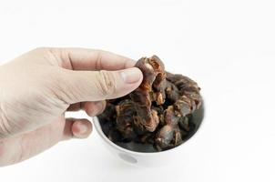 Hand holding sweet ripe tamarind  tropical fruit remove the seeds on white background photo