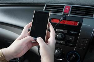 mano sostener teléfono inteligente en coche, gente prensa el teléfono mientras conducción foto