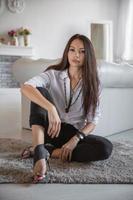 Charming young woman sitting by the sofa photo