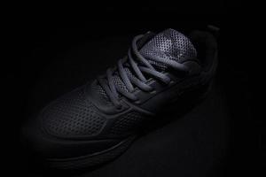 Black sneaker highlighted by studio light on a black background. photo