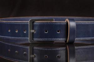 Part of a blue leather belt on a black background. photo