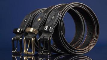 Group of black leather belts on a blue background. photo