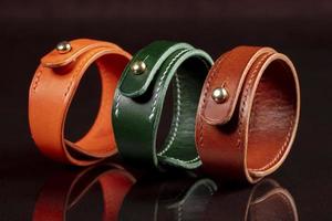 A group of multi-colored leather belts on a black background. photo