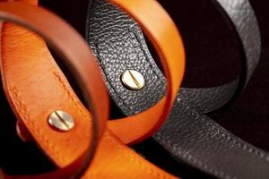 A group of multi-colored leather belts on a black background. photo