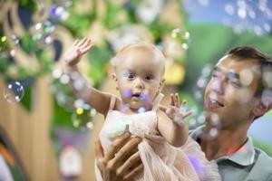 Dad's Day. Dad plays with his little daughter on the background of soap bubbles. photo