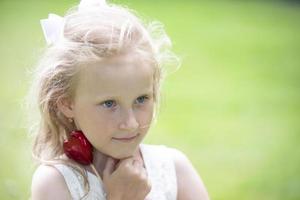 pequeño niña participación un pequeño rojo corazón. niño con un juguete corazón. foto