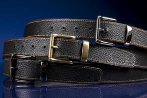 Group of black leather belts on a blue background. photo