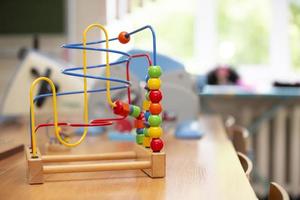 Children's toy labyrinth, maze on a metal spiral with ball, cylinder, cube on a wooden stand close-up photo