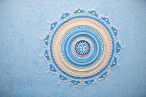 Round beautiful stucco pattern on the ceiling. Relief plaster, relief pattern blue background. Part of an old ceiling decorated with a clay pattern. photo