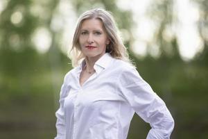 un hermosa de edad mediana europeo mujer. cincuenta años rubia mujer en un blanco camisa en el antecedentes de naturaleza. foto