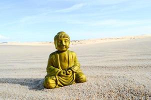 Small Buddha statue in the sand photo