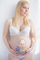 encantador embarazada mujer con un linda dibujo en su estómago foto
