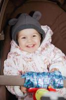 Cute little baby sitting in a stroller outdoors photo