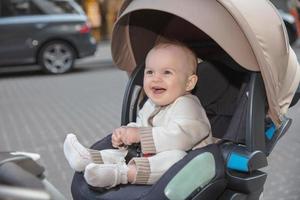 Cheerful little baby sitting in a strolle photo