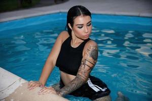 Young sexy brunette sitting in the pool photo