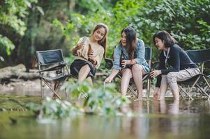 Group of women drink beer and soaked feet in stream photo