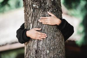 Contented young woman hugging a large tree with a blissful expression photo