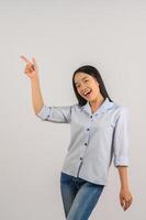 Portrait of young asian woman pointing with two hands and fingers to the side over isolated white background photo