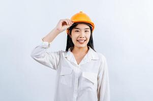 joven hembra ingeniero vistiendo amarillo casco estar con encantador sonrisa postura foto