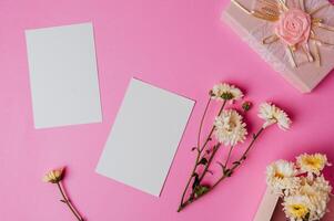 white paper and gift box on pink background decorated with flowers photo