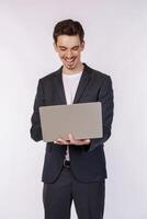 Portrait of young handsome smiling businessman holding laptop in hands, typing and browsing web pages isolated on white background photo