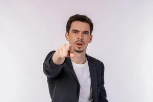 Portrait of attractive cheerful young man pointing finger at camera and standing isolated over background photo