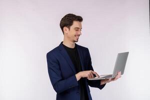 Portrait of young handsome smiling businessman holding laptop in hands, typing and browsing web pages isolated on white background photo