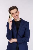 Portrait of Young smiling handsome businessman showing credit card isolated over white background photo