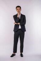 Portrait of young handsome businessman looking confident at the camera with smile with crossed arms and hand raised on chin over isolated background photo