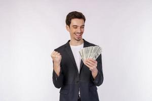 retrato de un hombre alegre que sostiene billetes de dólar y hace gesto de ganador apretando el puño sobre fondo blanco foto