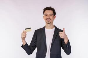 Portrait of Young smiling handsome businessman in casual clothes showing credit card and thumb up isolated over white background photo