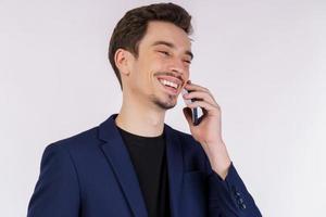 Close-up of happy handsome businessman talking by mobile phone and standing isolated over white background photo