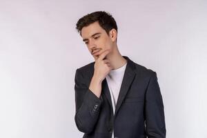 Portrait of young businessman thinking touching chin isolated over white background photo