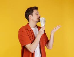 Portrait of a cheerful man holding dollar bills over yellow background photo