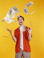 Portrait of happy young man throwing money up while standing isolated background photo