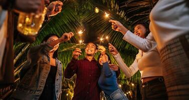 retrato de feliz grupo asiático de amigos divirtiéndose con bengalas al aire libre - jóvenes divirtiéndose con fuegos artificiales en la noche - gente, comida, estilo de vida de bebida, concepto de celebración de año nuevo. foto