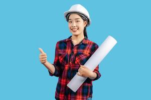 Young female engineer wearing white safety helmet with Blueprints photo