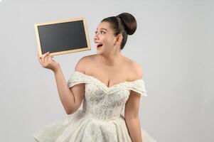 Young asian beautiful bride pose with blank blackboard in hand photo