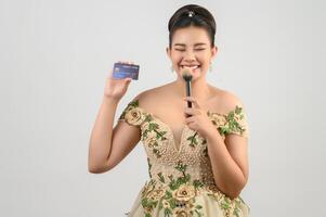 Young asian beautiful bride posting with credit card and beauty brush in hand photo