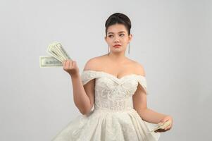 Young asian beautiful bride holding dollar bills and credit card in hand photo