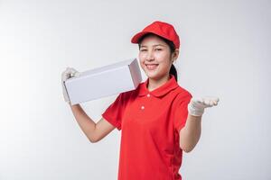 Image of  young delivery man in red cap blank t-shirt uniform standing with empty white cardboard box isolated on light gray background studio photo