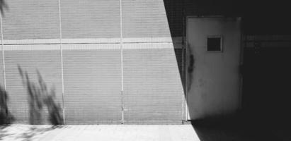 blanco antiguo entrada, acceso o cerrado puerta en oscuridad con gris o gris pared en luz de sol sombra y sombra para antecedentes en negro y blanco estilo. fondo de pantalla, Arte y exterior en monocromo tono. foto