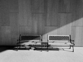 Two modern benches with sunlight and shadow from the side in the morning with concrete wall background and floor in black and white style with copy space. Object design in monochrome tone on cement. photo