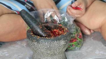 handbultande chili och vitlök i en granit murbruk är en kombination av Wokad basilika och doppning sås - en traditionell handgjord thai mat den där lägger till Mer smak till de utsökt mat. video