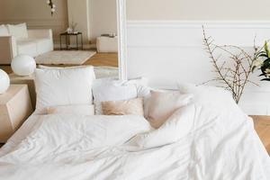 Bright cozy bed with pillows and a mirror. Scandinavian interior of the house photo