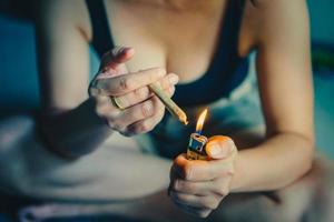 mujer preparando Encendiendo arriba cigarrillos con encendedor. canabis fumador laminación marijuana canabis articulación. drogas narcótico concepto. legal marijuana. foto