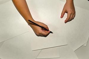 Close-up of children's hands drawing with a pencil on white paper. In the process of work. photo